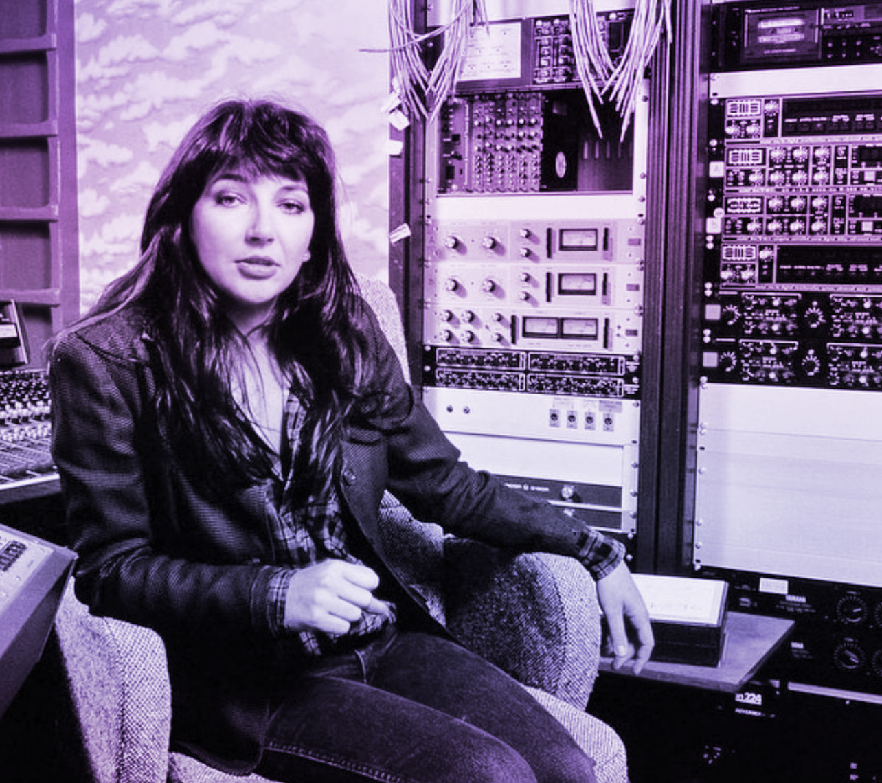 Kate Bush sitting at her recording studio with Recording equipment behind her